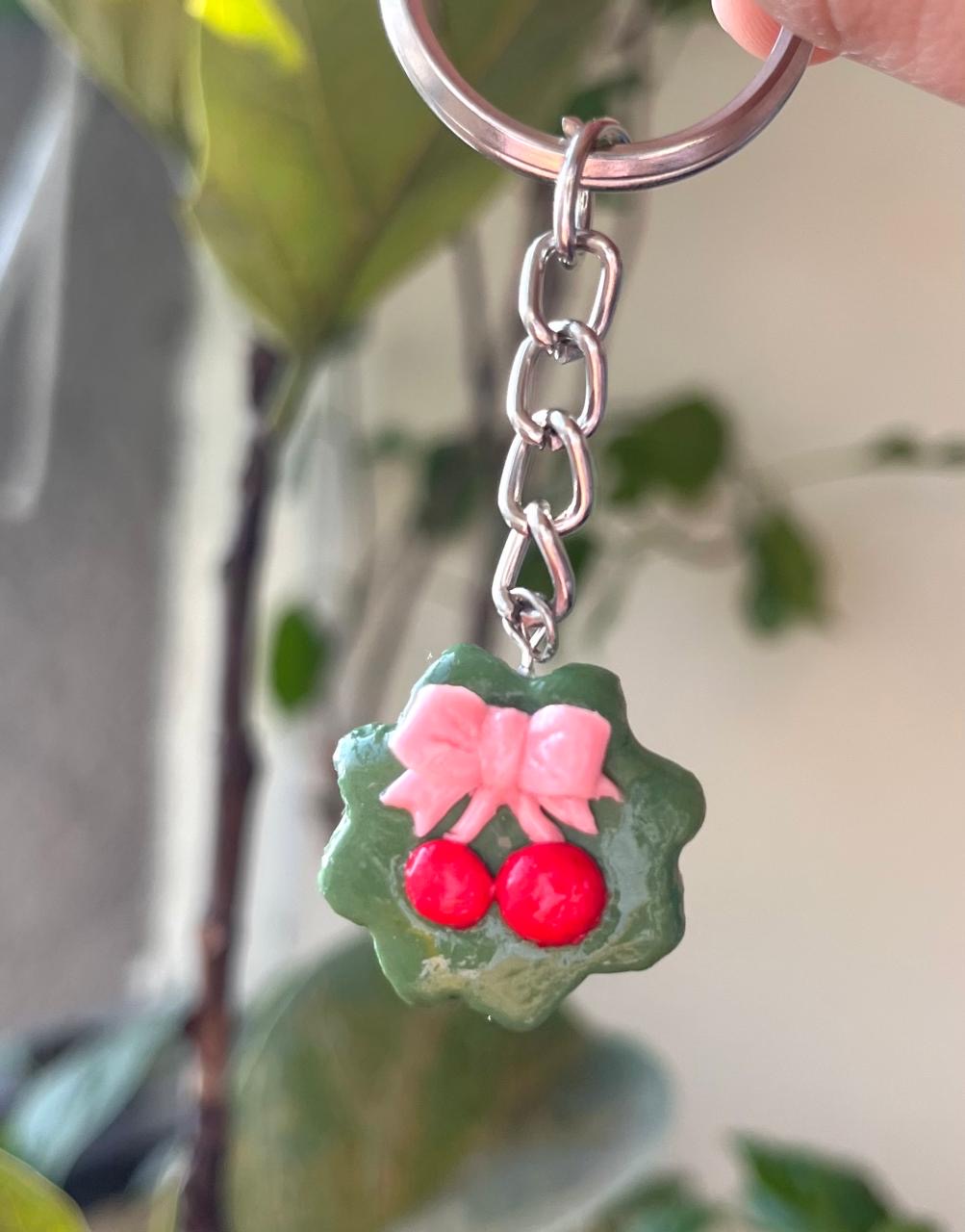 Green charm with pink bow and two red cherries