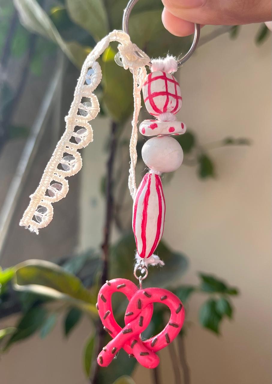 Pink pretzel-shaped treat and candy miniatures on a charm chain